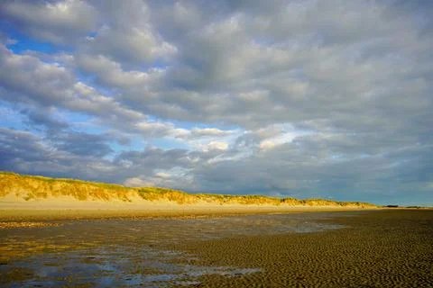 Cloudy sky over a sandy ocean shoreline 库存照片