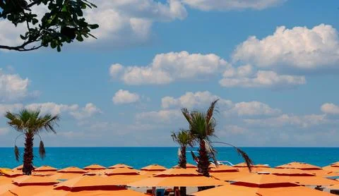Cloudy sky over the serene surface of the sea above the roofs of bright orange Stock Photos