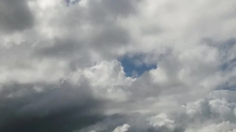 A cloudy sky with patches of blue peeking through the gray mass of clouds Stock Footage 338066206