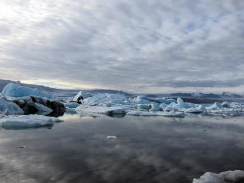 Cloudy sky reflected in glacial iceberg lagoon Stock Photos