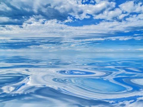 Cloudy sky reflected on swirls of cool, smooth water Stock Photos