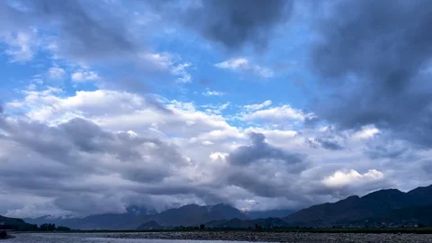 Cloudy Sky to Rocky Field Tilt Down with Mountains in Background Stock Footage 332855650