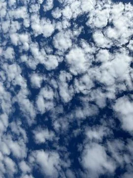 Cloudy sky with scattered white clouds on a deep blue background Stock Photos