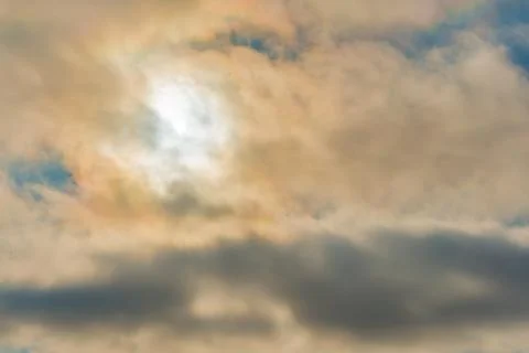 Cloudy sky, sun behind clouds. Strange view of a cloudy sky with the sun`s ra 스톡 사진
