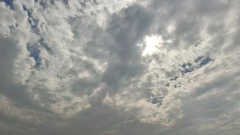Cloudy sky with sun shining through white puffy clouds on a blue day 스톡 사진
