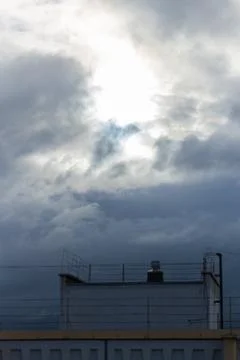 Cloudy sky with sunlight breaking through over a rooftop structure featuring Stock Photos
