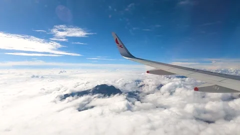 Cloudy sky view from airplane wing with mountain peak Stock Footage 330278628