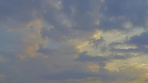 Cloudy sky with yellow and gray clouds at sunset Stock Photos