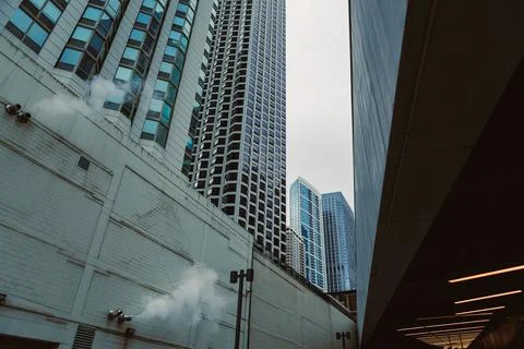 Cloudy skyline view between tall buildings in a city during the day with sm.. Stock Photos