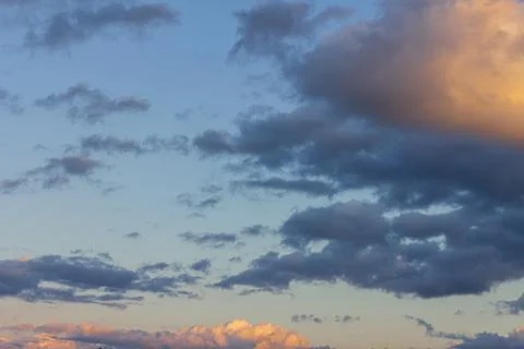 Cloudy soft clouds against the blue sky. The rays of the setting sun glide .. Stock-Fotos