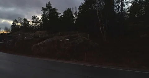 Cloudy sunset, Cinema 4k aerial rising view over a forest and a road on a isl Stock Footage 85584662