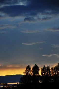 Cloudy sunset, clouds completely cover the solar disk. The sun sets in clouds Stock Photos