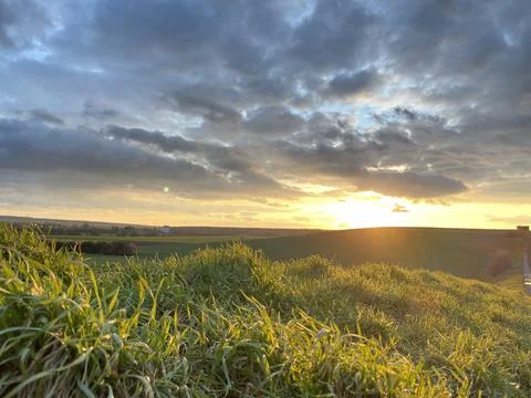 Cloudy sunset on the field Stock Photos