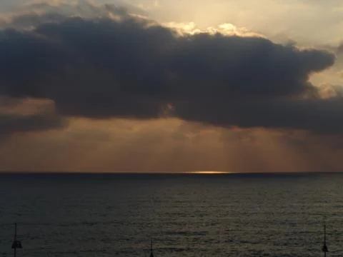 Cloudy sunset with light rays over the ocean 写真素材