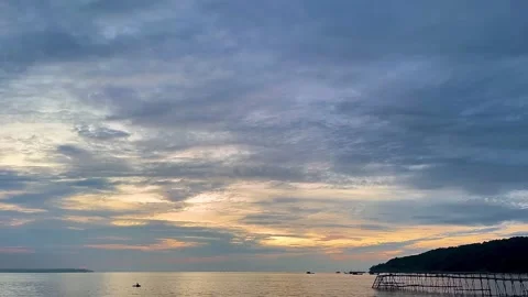 Cloudy Sunset Over Calm Sea with Coastal Silhouette and Traditional Structure Stock Footage 341036008