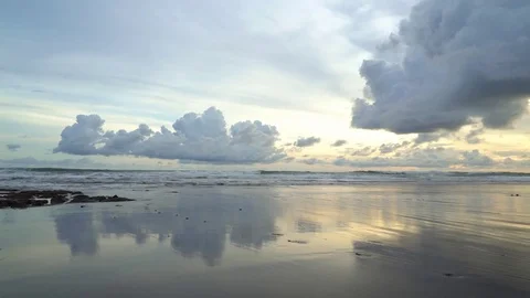 A cloudy sunset reflected in wet sand at the beach Stock Footage 74290176