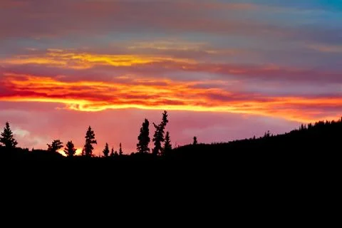 Cloudy sunset sky on fire and silhouette of forest Foto stock