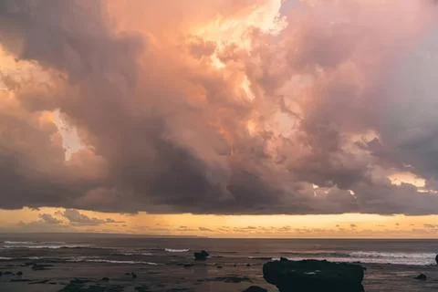 Cloudy sunset sky over the ocean with dark storm clouds Stock Photos
