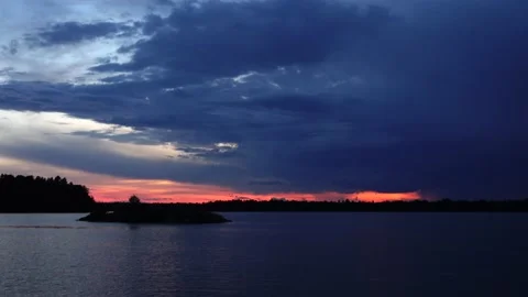 Cloudy twilight with a lightning over calm lake with an island Video stock 156066271