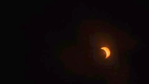Cloudy View of the Partial Solar Eclipse. Stock Photos