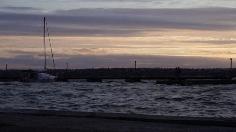 Cloudy warm orange evening sunset sky over yacht silhouette in river yacht port Stock Footage 92948502
