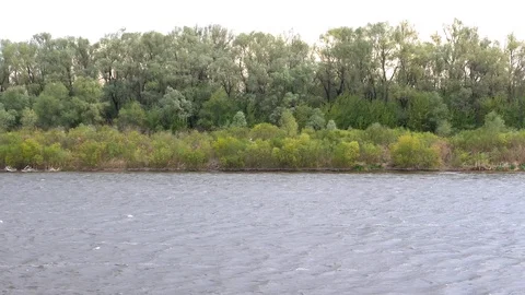 Cloudy weather, clouds, strong wind, rain over a large river. Shore with trees Stock Footage 129611402