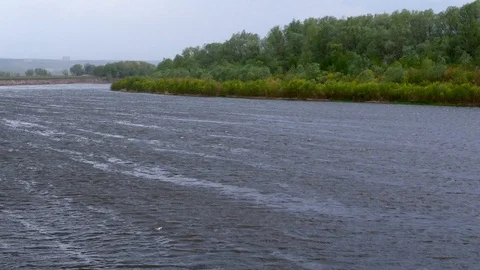 Cloudy weather, clouds, strong wind, rain over a large river. Shore with trees Stock Footage 129611405