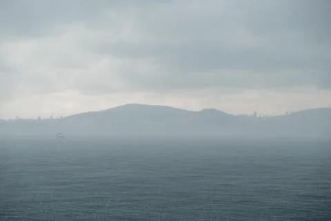 Cloudy weather over the Bosphorus with distant hills and a solitary boat Stock Photos