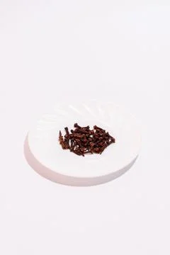 Cloves for cooking on a white background. Stack of nails on small plate Stock Photos
