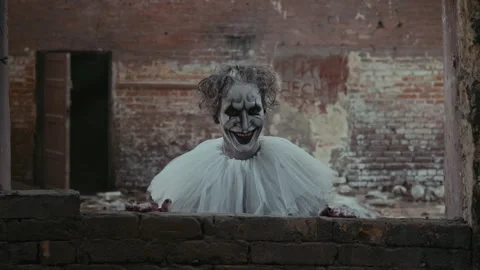Clown with Evil Smile Looking out Sharply from under Destroyed Wall Stock Footage 250943105