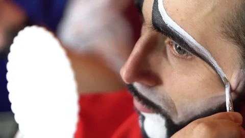 Clown puts a makeup on her eyebrows Stock Footage 84642359