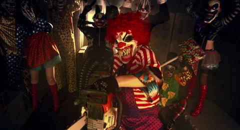 The clown in the red wig standing with a chainsaw. 库存影片 67871600