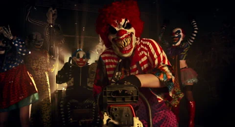 The clown in the red wig standing with a chainsaw. Vídeos de archivo 67871691