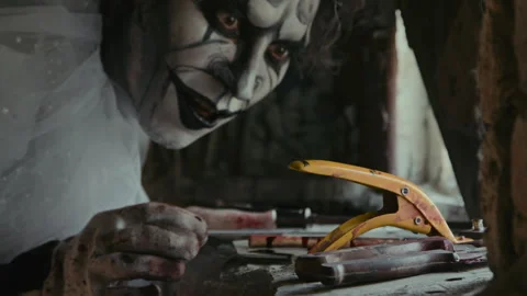 Clown with Scary Makeup Taking Pruner with His Teeth Stock Footage 250946940