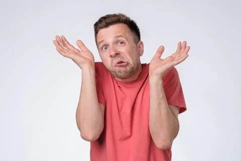 Clueless, funny looking young man holding arms out asking what is problem Stock Photos
