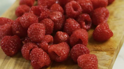 Cluster of bright, fresh raspberries on cutting board - closeup Stock Footage 341026443