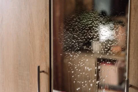 Cluster of cleaning foam dripping down a wardrobe mirror Foto stock