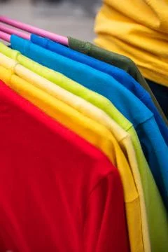 Cluster of colored plain t-shirts on hangers Stock Photos