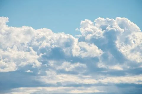 A cluster of cumulus thunderclouds in a bright blue sky during the daytime. Stock Photos