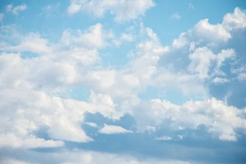 A cluster of cumulus thunderclouds in a bright blue sky during the daytime. Stock Photos