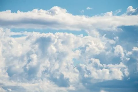 A cluster of cumulus thunderclouds in a bright blue sky during the daytime. Stock Photos