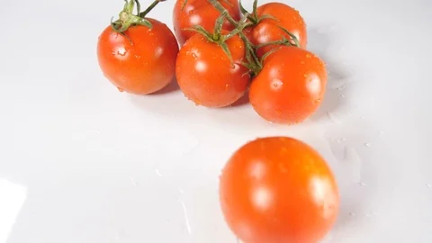 A cluster of fresh red tomatoes off the vine on a white background with water Stock Footage 88508187
