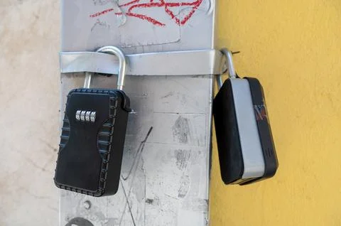 Cluster of key lockboxes hanging on drainpipe Stock Photos