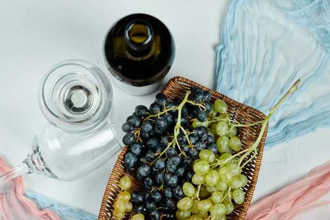 A cluster of mixed grapes in basket and glasses of wine and bottle Stock Photos