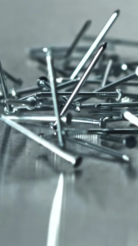 Cluster of pointed nails scattered on reflective platform Filmed on a high-speed Stock Footage 335395967