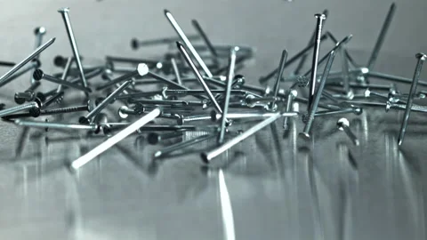 Cluster of pointed nails scattered on reflective platform Filmed on a high-speed Stock Footage 335412979