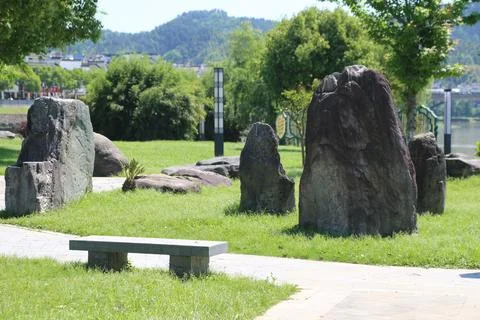 Cluster of upright landscape rocks rises from a green riverside lawn with t.. Stock Photos