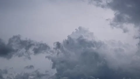 Clusters of gray rain clouds moving slowly across a hazy sky, reflecting th.. Stock Footage 300079602