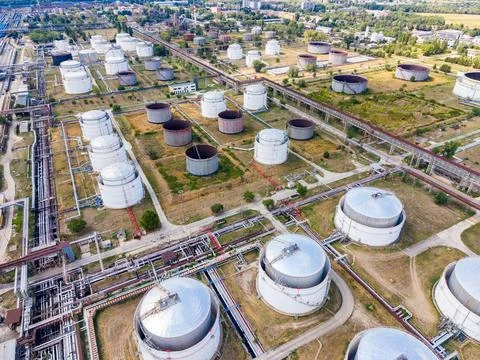 Clusters of large storage tanks are seen in an industrial area. Pipelines con Stock Photos