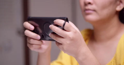 Clutching a digital mobile phone with both hands as the woman is playing Stock Footage 266204847
